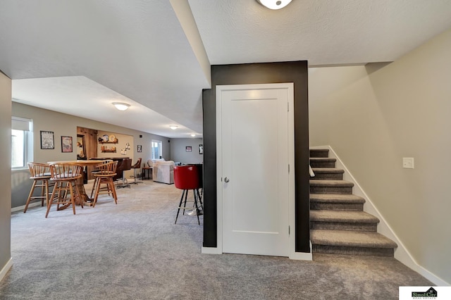 stairs with visible vents, a healthy amount of sunlight, indoor bar, and carpet