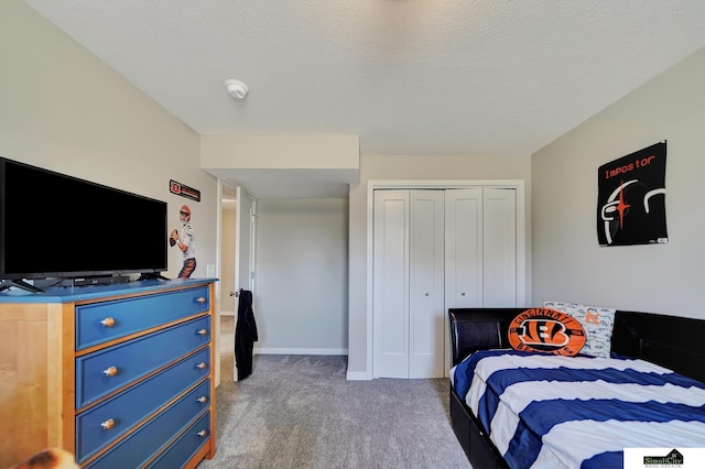 carpeted bedroom with a closet, baseboards, and a textured ceiling