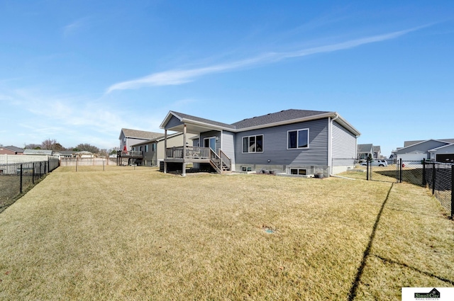 rear view of property featuring a yard, a deck, and a fenced backyard