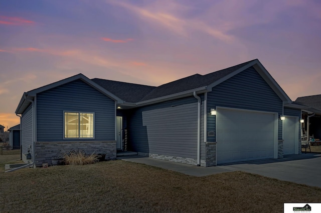 single story home featuring a yard, stone siding, concrete driveway, and an attached garage