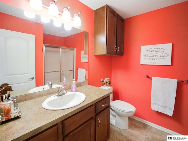 bathroom featuring tile patterned flooring, baseboards, toilet, a stall shower, and vanity