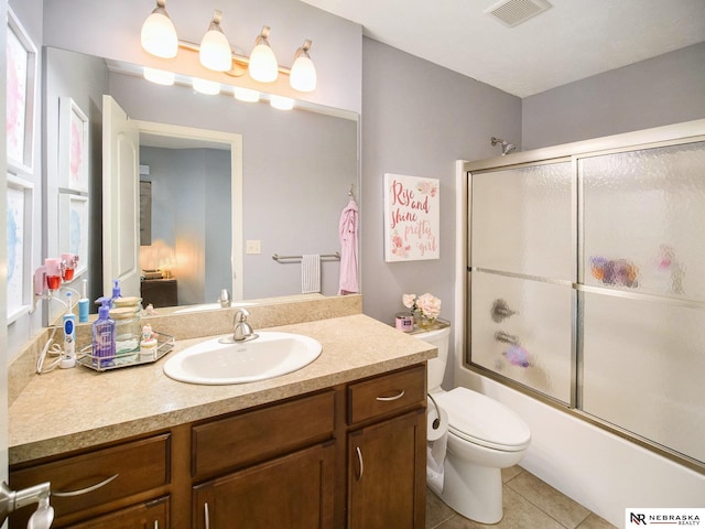 full bathroom with visible vents, toilet, combined bath / shower with glass door, tile patterned flooring, and vanity