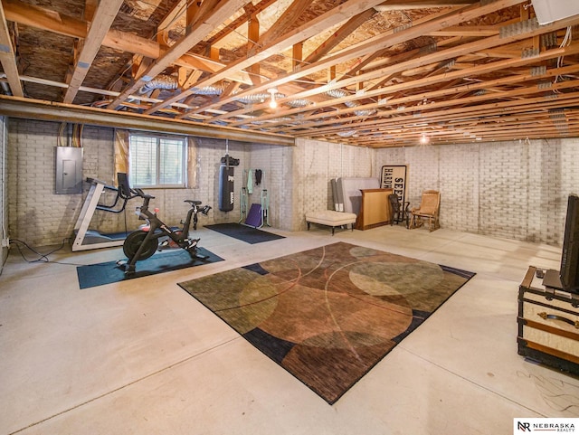 exercise room with electric panel, water heater, and brick wall