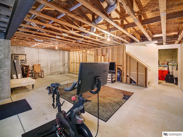 unfinished basement featuring brick wall and stairs