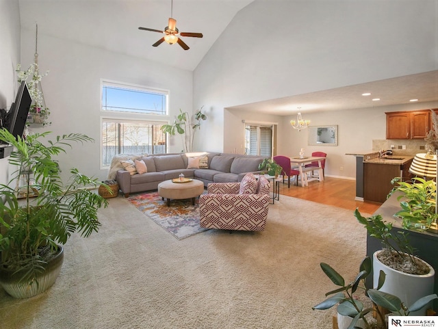 living area featuring ceiling fan with notable chandelier, recessed lighting, light colored carpet, and high vaulted ceiling