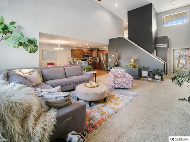 living area featuring a wealth of natural light, a notable chandelier, light colored carpet, and a towering ceiling