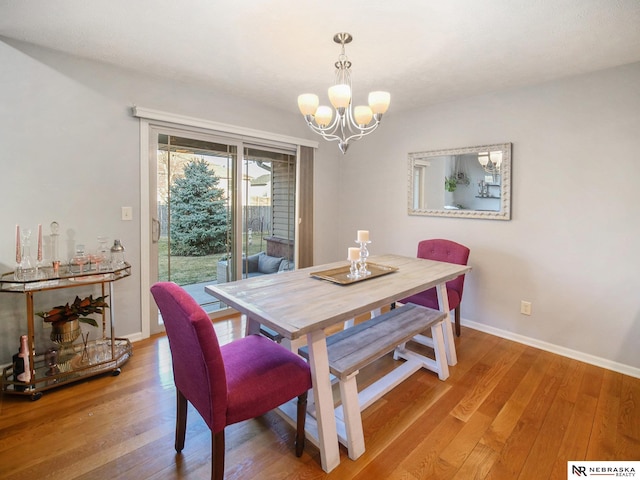 dining area featuring an inviting chandelier, light wood-style floors, and baseboards