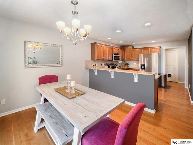 dining room featuring an inviting chandelier, recessed lighting, light wood-style floors, and baseboards