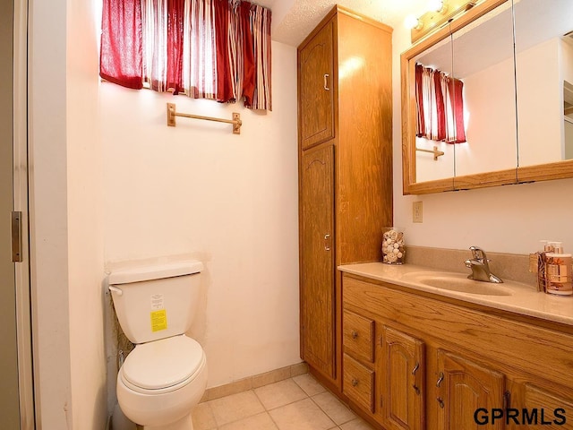 bathroom featuring tile patterned flooring, toilet, vanity, and baseboards