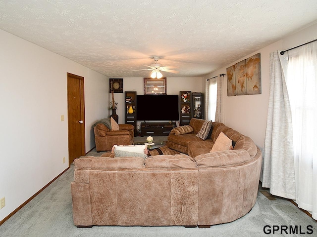 carpeted living area featuring baseboards, a textured ceiling, and a ceiling fan