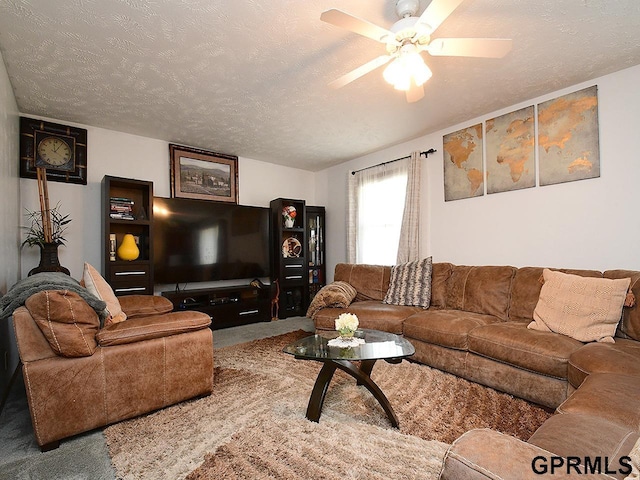 carpeted living room with a ceiling fan and a textured ceiling