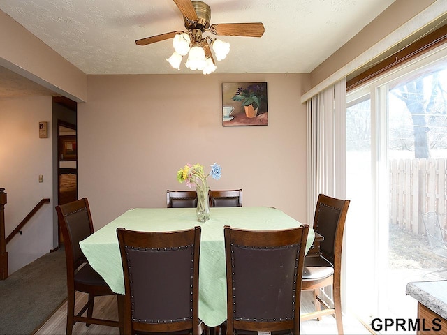 dining space with ceiling fan, carpet floors, and a textured ceiling