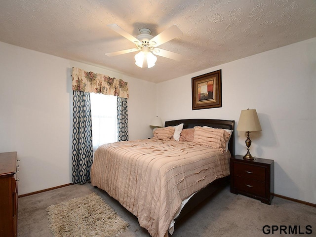 bedroom with baseboards, ceiling fan, a textured ceiling, and carpet