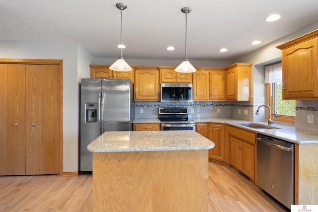 kitchen featuring backsplash, a kitchen island, light wood-type flooring, appliances with stainless steel finishes, and a sink