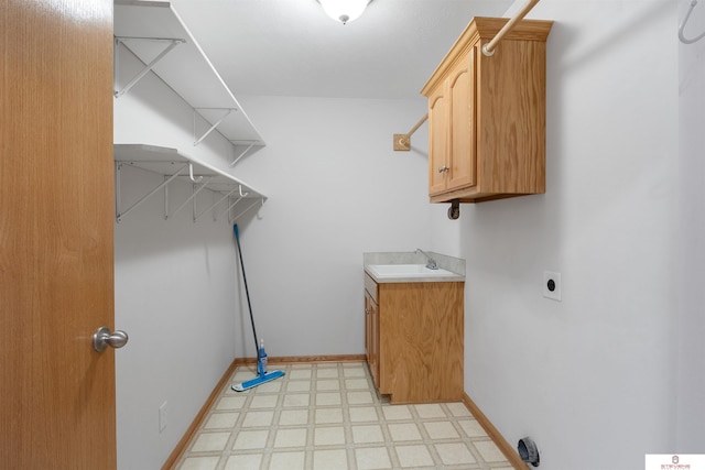 washroom featuring baseboards, light floors, cabinet space, hookup for an electric dryer, and a sink