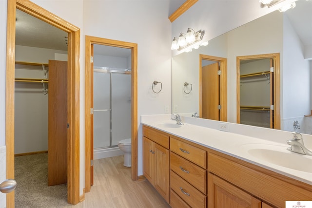 bathroom featuring double vanity, toilet, a shower stall, and a sink