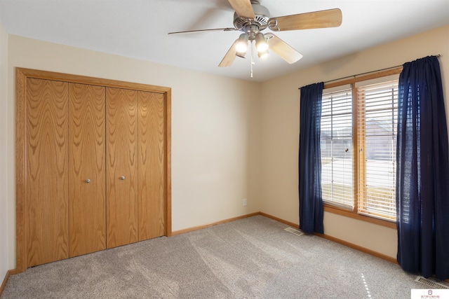 unfurnished bedroom with a closet, multiple windows, baseboards, and carpet