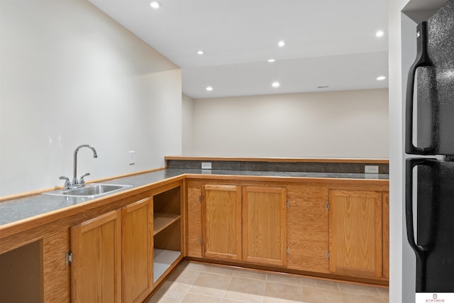 kitchen with brown cabinetry, light tile patterned flooring, recessed lighting, freestanding refrigerator, and a sink