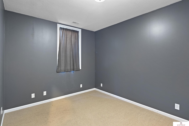 empty room with carpet flooring, visible vents, baseboards, and a textured ceiling