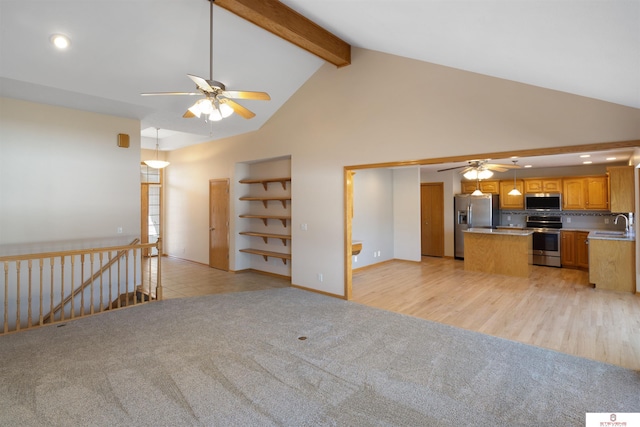 unfurnished living room featuring high vaulted ceiling, a sink, ceiling fan, beamed ceiling, and light colored carpet