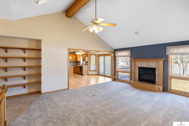 unfurnished living room featuring light carpet, beam ceiling, a tile fireplace, and a ceiling fan