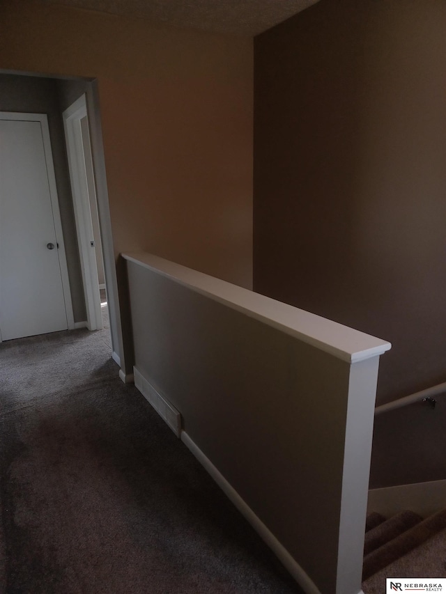 hallway featuring an upstairs landing, baseboards, and carpet