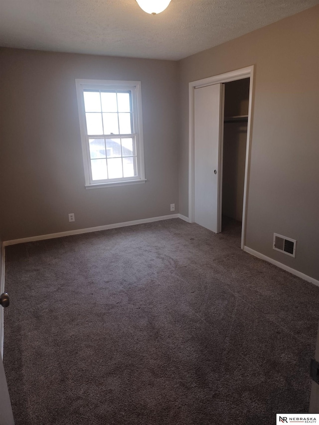 unfurnished bedroom featuring baseboards, visible vents, carpet floors, and a textured ceiling