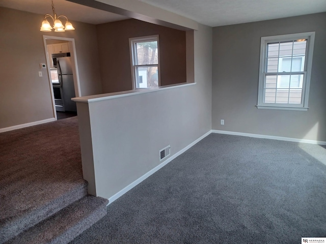 empty room featuring visible vents, baseboards, and dark colored carpet