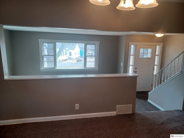 entrance foyer with visible vents, baseboards, stairs, carpet floors, and a notable chandelier