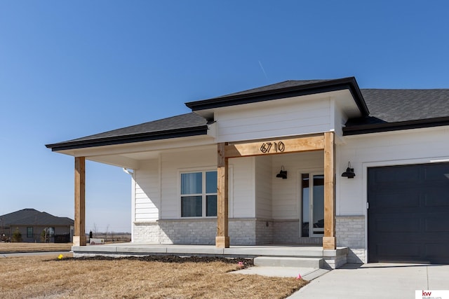 view of front of house featuring a porch, a garage, and roof with shingles