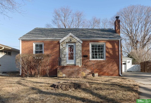 view of front of house featuring brick siding, a chimney, and roof with shingles