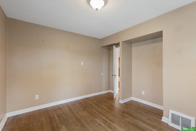 empty room with visible vents, baseboards, and wood finished floors