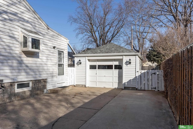 detached garage with concrete driveway and fence