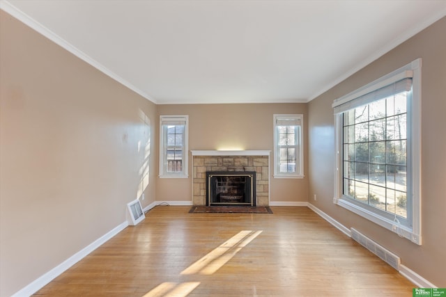 unfurnished living room featuring baseboards, crown molding, a fireplace, and light wood finished floors