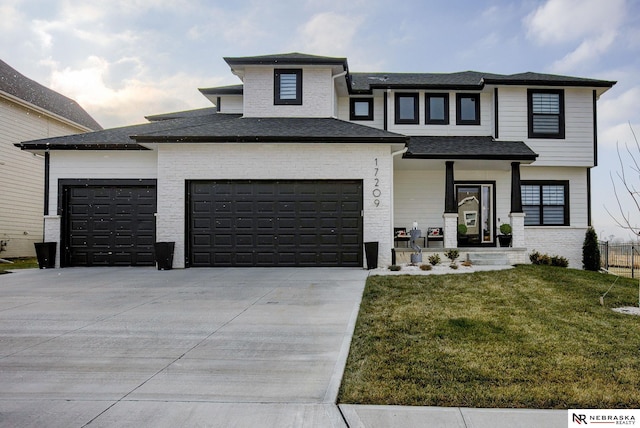 prairie-style home with a front lawn, an attached garage, brick siding, and driveway