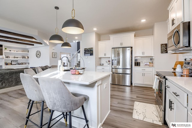 kitchen featuring appliances with stainless steel finishes, open floor plan, white cabinets, and light countertops