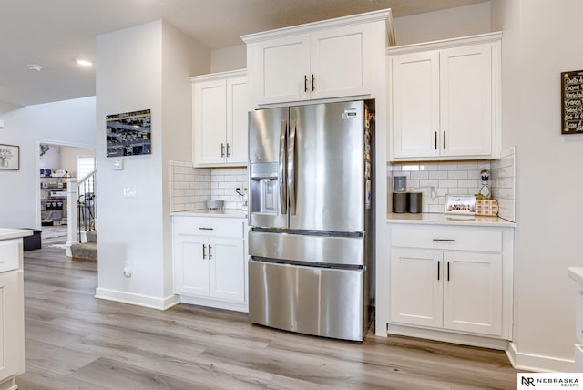 kitchen with white cabinetry, light wood-style floors, stainless steel fridge with ice dispenser, and light countertops