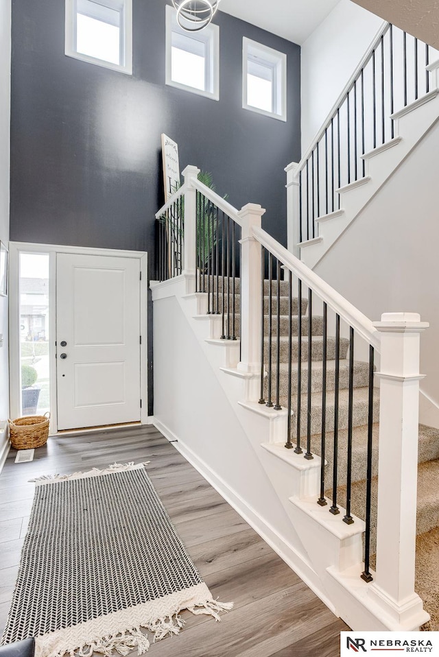 foyer entrance with stairway, a high ceiling, and wood finished floors