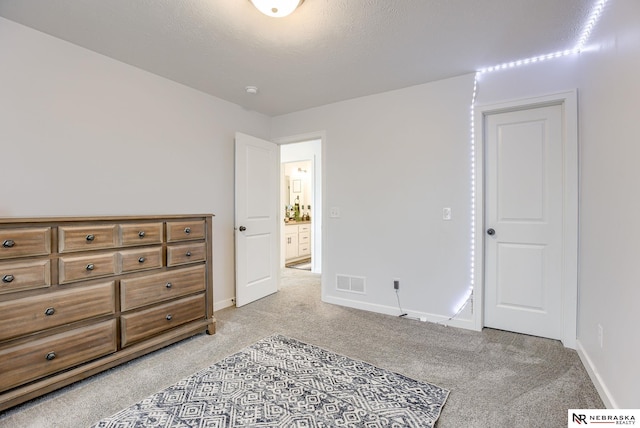 bedroom featuring visible vents, baseboards, light colored carpet, and a textured ceiling