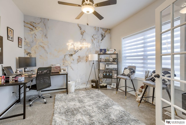 carpeted office space featuring ceiling fan with notable chandelier