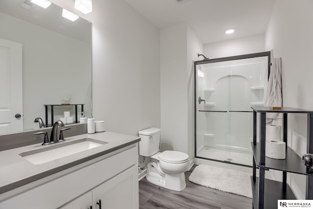 full bathroom with a shower stall, toilet, vanity, and wood finished floors