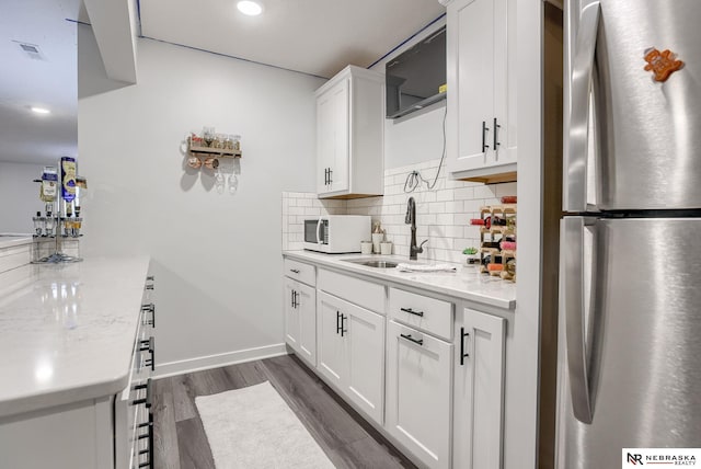 kitchen with visible vents, dark wood-type flooring, decorative backsplash, freestanding refrigerator, and a sink