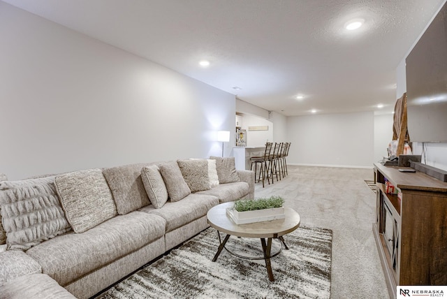 living room featuring recessed lighting, baseboards, light carpet, and a textured ceiling