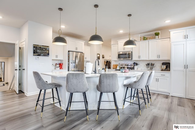 kitchen with white cabinetry, light countertops, light wood-style floors, and appliances with stainless steel finishes