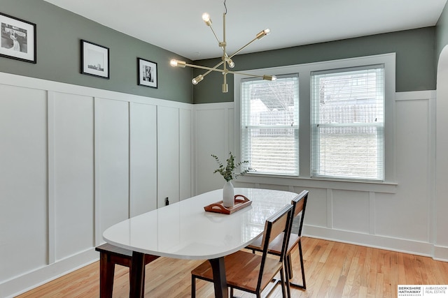 dining room with a decorative wall, visible vents, light wood-type flooring, and an inviting chandelier