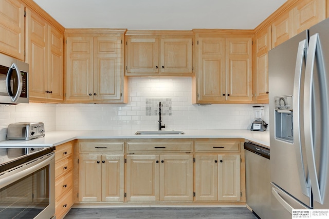 kitchen featuring a sink, appliances with stainless steel finishes, and light brown cabinetry