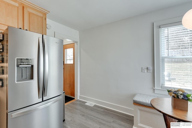 kitchen with a wealth of natural light, stainless steel fridge, light wood-style flooring, and light brown cabinets