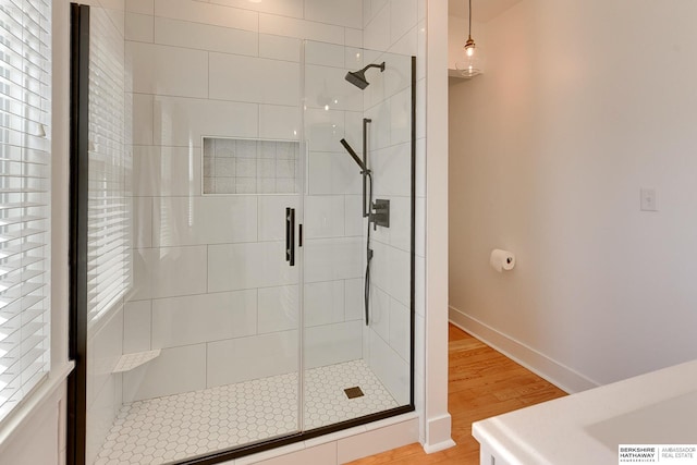 bathroom with a shower stall, baseboards, and wood finished floors