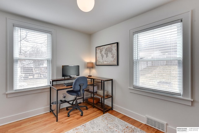 office space with wood finished floors, visible vents, a wealth of natural light, and baseboards