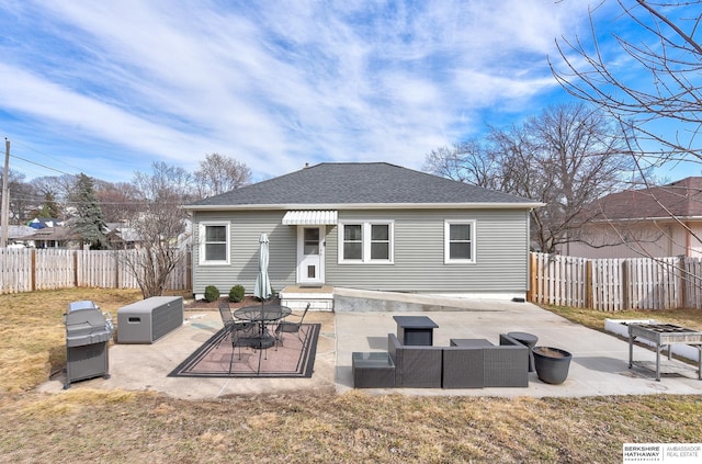 back of house featuring roof with shingles, an outdoor living space with a fire pit, a fenced backyard, and a patio area